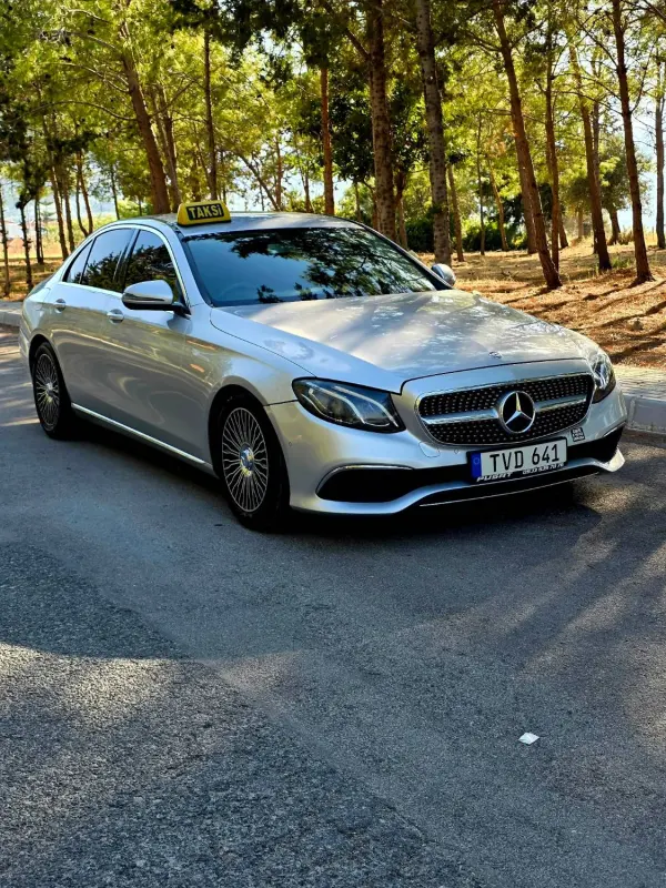 Silver Mercedes E-Class taxi on a pine-lined road in North Cyprus
